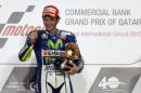 Movistar Yamaha MotoGP rider Valentino Rossi of Italy celebrates with his trophy on the podium after winning the MotoGP race of the Qatar Grand Prix on March 29, 2015