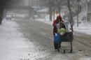A man pushes a cart up the road while scavenging for bottles and cans during a winter nor'easter snowstorm in Lynn