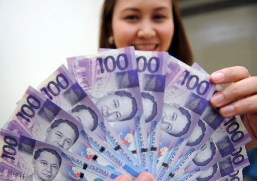 A bank employee displays 100 peso notes in Manila. The Philippine economy is facing major risks from abroad that could limit its growth prospects next year, the central bank governor said Wednesday