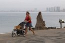 A woman pushes her dog in a baby stroller along the beach in the resort city of Puerto Vallarta, Mexico, Friday, May 25, 2012. Hurricane Bud lost a little of its sting early Friday, but remained a potent Category 2 storm as it headed toward a string of laid-back beach resorts and small mountain villages on Mexico's Pacific coast south of Puerto Vallarta. (AP Photo/Bruno Gonzalez)
