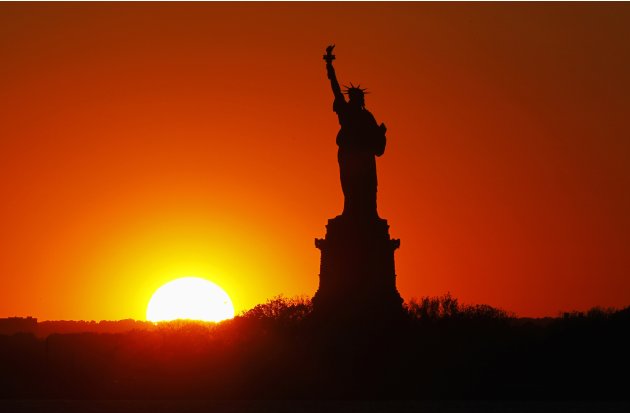 The sun sets behind the Statue of Liberty in New York