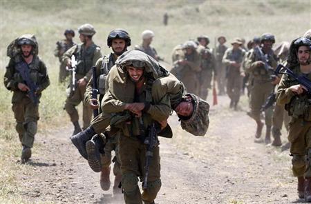 An Israeli soldier carries another soldier as they walk with their comrades during training close to the ceasefire line between Israel and Syria on the Israeli occupied Golan Heights May 7, 2013. REUTERS/Baz Ratner
