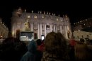 People in Saint Peter's Square watch a live television screen showing black smoke rising from the chimney above the Sistine Chapel at the Vatican
