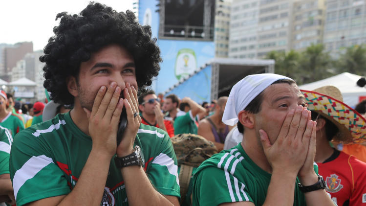 Mexico soccer fans react after a second goal was scored against their team as they watch the World Cup round of 16 match against Netherlands on a live telecast inside the FIFA Fan Fest area on Copacabana beach in Rio de Janeiro, Brazil, Sunday, June 29, 2014. The Netherlands staged a dramatic late comeback, scoring two goals in the dying minutes to beat Mexico 2-1 and advance to the World Cup quarterfinals. (AP Photo/Leo Correa)