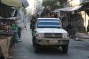 Free Syrian Army fighters ride on a vehicle past empty merchandise stalls in Aleppo's rebel-controlled Bustan al-Qasr neighbourhood due to a siege by Syrian pro-government forces that cut the supply lines into opposition-held areas of the city