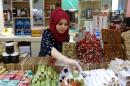 In this Wednesday, April 29, 2015 photo, Rahaf Abdullah works at a sweets shop at a mall in Irbil, in Iraq's Kurdish region. Two years after fleeing from her home in Damascus, the 22-year-old is selling sweets to local women who largely refuse to take such jobs. 