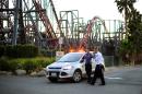 Members of the Six Flags Magic Mountain amusement park security staff monitor the situation at the exit of the park after riders were injured on the Ninja coaster, not shown, Monday, July 7, 2014, in Valencia, Calif. The roller coaster hit a tree branch dislodging the front car, leaving four people slightly injured and keeping nearly two dozen summer fun-seekers hanging 20 to 30 feet in the air for hours as day turned to night. Two of the four people hurt on the Ninja coaster were taken to the hospital as a precaution, but all the injuries were minor, fire and park officials said. (AP Photo/Los Angeles Daily News, Andy Holzman)