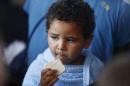 A migrant child eats emergency ration food on the MOAS ship MV Phoenix after being rescued from an overloaded wooden boat 10.5 miles off the coast of Libya