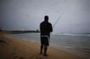 A man fishes as a cluster of storms passes through the area, in San Juan, Puerto Rico, Friday, Aug. 22, 2014. The National Weather Service in San Juan said the region could be hit with up to 6 inches (15 centimeters) of rain and wind gusts of 35 mph (56 kph). (AP Photo/Ricardo Arduengo)