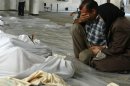A Shaam News Network photo shows a Syrian couple mourning in front of bodies wrapped in shrouds on August 21, 2013