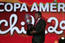 The president of the Uruguayan Football Federation, Wilmar Valdez, enters the stage holding the championship trophy, before the draw for the 2015 Copa America, in Vina del Mar, Chile, Monday, Nov. 24, 2014. Chile will host the 2015 international soccer tournament in June and July. (AP Photo/Luis Hidalgo)