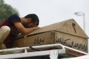 In this photo taken on Monday, May 20, 2013, Ali Karim weeps over his daughter's coffin before her burial in the holy Shiite city of Najaf, 160 kilometers (100 miles) south of Baghdad, Iraq. A wave of car bombings across Baghdad's Shiite neighborhoods and in the southern city of Basra killed and wounded dozens of people, police said. (AP Photo/ Alaa al-Marjani)