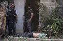 In this April 7, 2013 photo, police stand next to the body of a man who was killed during a shootout with police who were carrying out an offensive against gang members in Tegucigalpa, Honduras. The officers had surrounded a house where two gangsters had holed up after a chase with police. (AP Photo/Fernando Antonio)