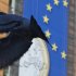 A pigeon flies in front of a giant banner for the euro currency in front of EU headquarters in Brussels on Tuesday, Nov. 20, 2012. European Union officials will make a fresh try Tuesday to reaching a political accord on desperately needed bailout loans to Greece, an agreement that eluded them last week. (AP Photo/Virginia Mayo)