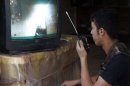 A Free Syrian Army fighter uses a walkie-talkie to talk with a fellow fighter as he watches a surveillance monitor in Deir al-Zor