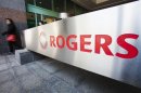 A woman walks by a sign at the Rogers Communications headquarters building on the day of their annual general meeting for shareholders in Toronto