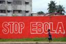 A girl walks past a slogan painted on a wall reading "Stop Ebola" in Monrovia on August 31, 2014