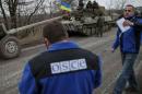 Members of Special Monitoring Mission of the Organization for Security and Cooperation (OSCE) to Ukraine walk along a convoy of the Ukrainian armed forces in Paraskoviyvka