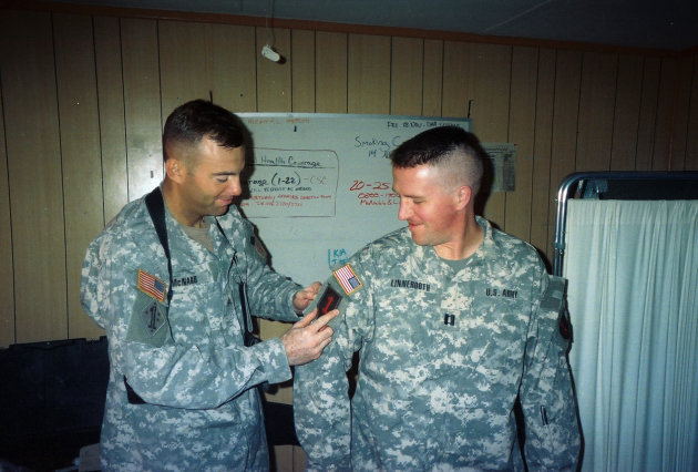 In this Autumn 2006 photo provided by Brock McNabb, McNabb places a "combat patch" on Pete Linnerooth's uniform at their office in Baghdad, denoting that he had been in-country long enough to earn the badge of honor and is officially a combat veteran. Capt. Linnerooth was an Army psychologist who counseled soldiers during some of the fiercest fighting in Iraq. Hundreds upon hundreds sought his help. For nightmares and insomnia. For shock and grief. And for reaching that point where they just wanted to end it all. Linnerooth did such a good job his Army comrades dubbed him The Wizard. His "magic" was deceptively simple: an instant rapport with soldiers, an empathetic manner, a big heart. (AP Photo/Brock McNabb)