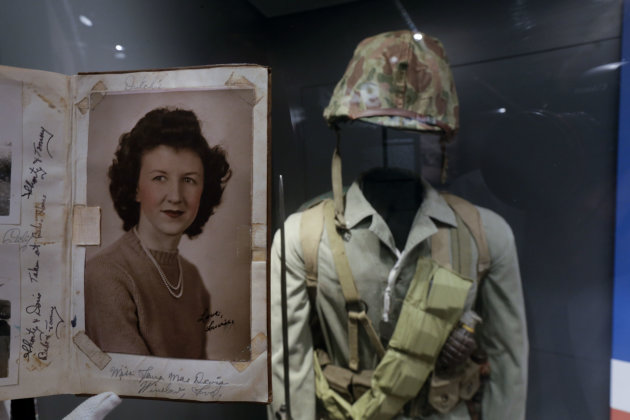 In this May 23, 2013 photo, a page of out of the diary of 22-year-old Marine Cpl. Thomas Jones featuring a photo of his high school sweetheart, Laura Mae Davis Burlingame, is on display at the National WWII Museum in New Orleans. Behind is a Marine uniform like one Jones, who died in the bloody assault on a Japanese-held island during World War II, would have worn. Before Jones died, he wrote what he called his “last life request” to anyone who might find his diary: Please give it to Laura Mae Davis, the girl he loved. Laura Mae Davis Burlingame _ she married an Army Air Corps man in 1945 _ had given the diary to Jones, and didn’t know it had survived him until visiting the museum on April 24. (AP Photo/Gerald Herbert)