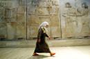 An Iraqi woman walks in front of Assyrian mural sculptures July 3, 2003 as the Baghdad museum briefl..