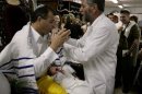 An eight day-old baby is held during his circumcision ceremony in Haifa