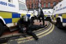 A police officer is tended to by a colleague after Loyalist protesters attacked the police with bricks and bottles as they waited for a republican parade to make its way through Belfast City Centre
