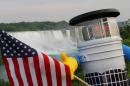 This undated photo courtesy of hitchBOT shows hitchBOT posing with the US flag at Niagra Falls