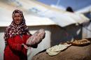 A displaced Iraqi woman, who fled her home due to attacks by jihadists from the Islamic State group, bakes bread at the Harsham refugee camp outside Arbil, Iraq, on October 22, 2014
