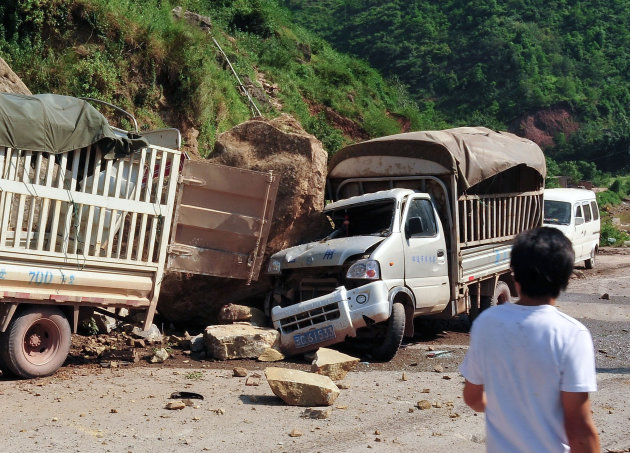 A man looks at the trucks damaged by fallen rocks after an earthquake in Zhaotong town, Yiliang County, southwest China's Yunnan Province, Friday, Sept. 7, 2012. A series of earthquakes collapsed houses and triggered landslides Friday in a remote mountainous part of southwestern China where damage was preventing rescues and communications were disrupted. At least 64 deaths have been reported. (AP Photo) CHINA OUT