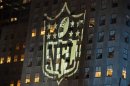 A man stands at a window lit by the NFL logo in New York