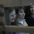 Members of the female punk band "Pussy Riot" sit in a glass-walled cage before a court hearing in Moscow