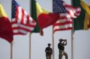 American security officers scan airport from rooftop below Senegalese and American flags before departure of U.S. President Obama in Dakar