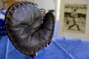 This photo taken on Monday, June 30, 2014, shows a Lou Gehrig signed baseball mitt and autographed picture given to Howard Henderson, who played catch with Gehrig as a boy, at Henderson's Greenwich, Conn., home Monday, June 30, 2104. Gehrig, a Yankee first baseman and a friend of Henderson's songwriter father, visited his home and Henderson visited him when he had ALS. The mitt that was autographed by Gehrig with a hot instrument, will be auctioned in July, expecting to fetch $200,000 to $300,000. (AP Photo/Craig Ruttle)