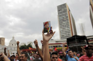 A "Chavista" demonstrator, and supporter of President-elect Nicolas Maduro, holds a photo of the late President Hugo Chavez during a march in front of the National Electoral Council (CNE) in Caracas, Venezuela, Wednesday, April 17, 2013. Opposition candidate Henrique Capriles has presented a series of allegations of vote fraud and other irregularities to back up his demand for a vote-by-vote recount for the presidential election. Maduro, the hand-picked successor of the late Hugo Chavez, was declared the winner by 262,000 votes out of 14.9 million cast, and Capriles contends the purported abuses add up to more than Maduro's winning margin. (AP Photo/Ramon Espinosa)