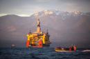 FILE - In this April 17, 2015 file photo, with the Olympic Mountains in the background, a small boat crosses in front of the Transocean Polar Pioneer, a semi-submersible drilling unit that Royal Dutch Shell leases from Transocean Ltd., as it arrives in Port Angeles, Wash., aboard a transport ship after traveling across the Pacific before its eventual Arctic destination. The U.S. government on Monday gave Shell the final permit it needs to drill for oil in the Arctic Ocean off Alaska's northwest coast for the first time in more than two decades. (Daniella Beccaria/seattlepi.com via AP, File) MAGS OUT; NO SALES; SEATTLE TIMES OUT; TV OUT; MANDATORY CREDIT