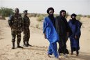 Malian soldiers stand next to Tuareg men in the village of Tashek, outside Timbuktu