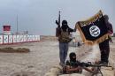 Islamic State militants pose with the trademark jihadist flag