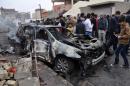 Iraqis inspect a burnt-out car at the scene of car bomb explosion in the multi-ethnic northern Iraqi city of Kirkuk, on January 26, 2014