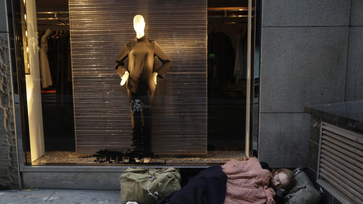 FILE - In this Wednesday, Nov. 20, 2013, file photo, a destitute man sleeps on the sidewalk under a holiday window at Blanc de Chine, in New York. A Gallup poll found two-thirds of Americans are dissatisfied with the nation’s distribution of wealth. (AP Photo/Mark Lennihan, File)