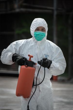 A health official, wearing a mask and protective suit, …