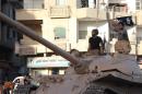 An image made available by Jihadist media outlet Welayat Raqa on June 30, 2014, allegedly shows a member of the IS (Islamic state) militant group parading with a tank in a street in the northern Syrian city of Raqa