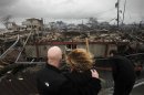 Robert Connolly, left, embraces his wife Laura as they survey the remains of the home owned by her parents that burned to the ground in the Breezy Point section of New York, Tuesday, Oct. 30, 2012. More than 50 homes were destroyed in the fire which swept through the oceanfront community during superstorm Sandy. At right is their son, Kyle. (AP Photo/Mark Lennihan)