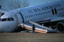 A person walks around a damaged US Airways jet at the end of a runway at the Philadelphia International Airport, Thursday, March 13, 2014, in Philadelphia. Airline officials said the flight was heading to Fort Lauderdale, Fla., when the pilot was forced to abort takeoff around 6:30 p.m., after the front landing gear failed. An airport spokeswoman said no injuries have been reported. (AP Photo/Matt Slocum)