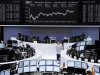 Traders work at their desks in front of the Dax board at the Frankfurt stock exchange