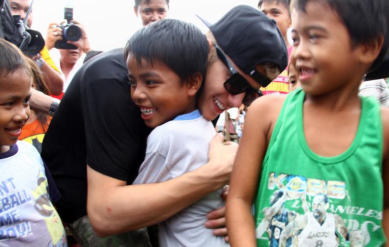 Canadian pop megastar Justin Bieber (C, black shirt) hugs a young survivor of Super Typhoon Haiyan in Palo, Leyte province on December 10, 2013