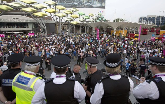 Police officers look on as people at Stratford Station queue to get into the Olympic Park for the opening ceremony of the 2012 Olympic Games in London