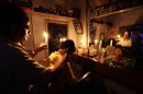 An Indian barber holding a candle, has a haircut for a customer at his shop in Kolkata, India, Tuesday, July 31, 2012. India's energy crisis cascaded over half the country Tuesday when three of its regional grids collapsed, leaving 620 million people without government-supplied electricity for several hours in, by far, the world's biggest blackout. (AP Photo/Bikas Das)