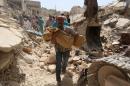A Syrian man carries a body after it was removed from the rubble of buildings following a reported barrel bomb attack by government forces on the Qadi Askar district of Aleppo on May 20, 2015