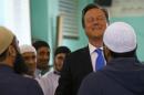 Britain's Prime Minister David Cameron laughs as he speaks to men during a visit to the Jamia Mosque in Manchester